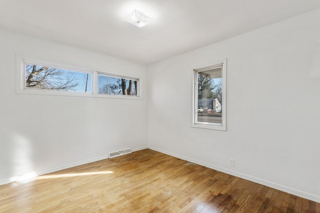 empty room featuring visible vents, plenty of natural light, baseboards, and light wood-style flooring