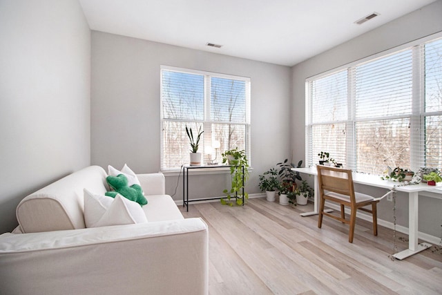 living area featuring baseboards, visible vents, and light wood-type flooring