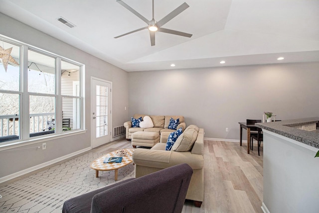 living room with vaulted ceiling, light wood-style floors, visible vents, and baseboards