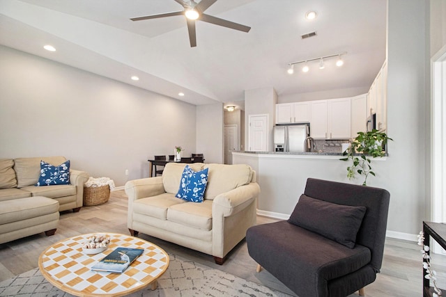 living room featuring light wood finished floors, visible vents, baseboards, and vaulted ceiling