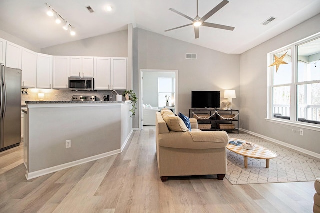 living room featuring visible vents, light wood-style floors, and vaulted ceiling