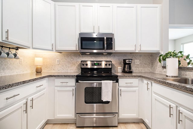 kitchen featuring decorative backsplash, white cabinets, and appliances with stainless steel finishes