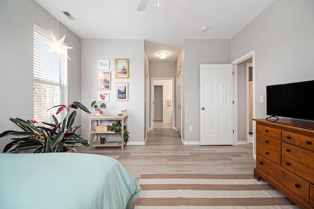 bedroom with visible vents, connected bathroom, light wood-style floors, baseboards, and ceiling fan