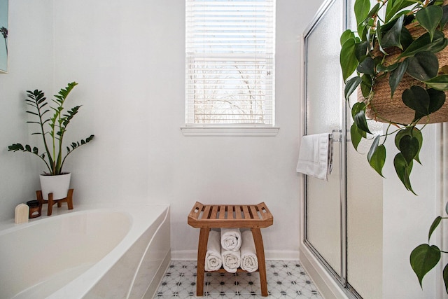 bathroom featuring tile patterned floors, a bath, baseboards, and a stall shower