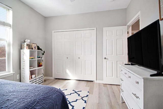 bedroom with a closet, multiple windows, baseboards, and light wood finished floors