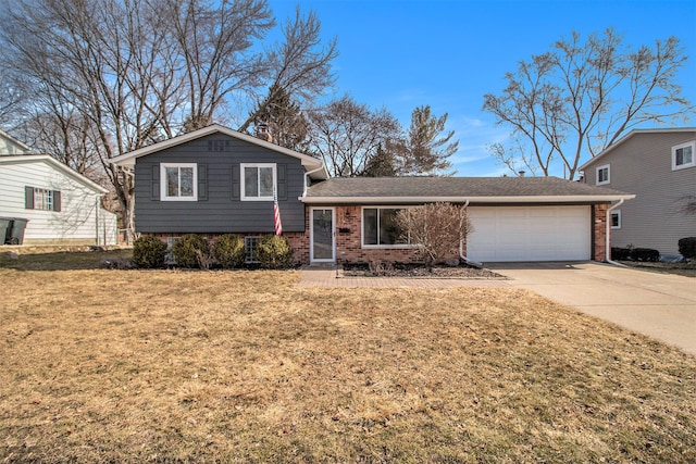 split level home featuring brick siding, an attached garage, concrete driveway, and a front yard