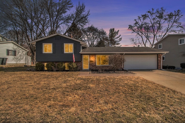 split level home featuring a garage, brick siding, and driveway