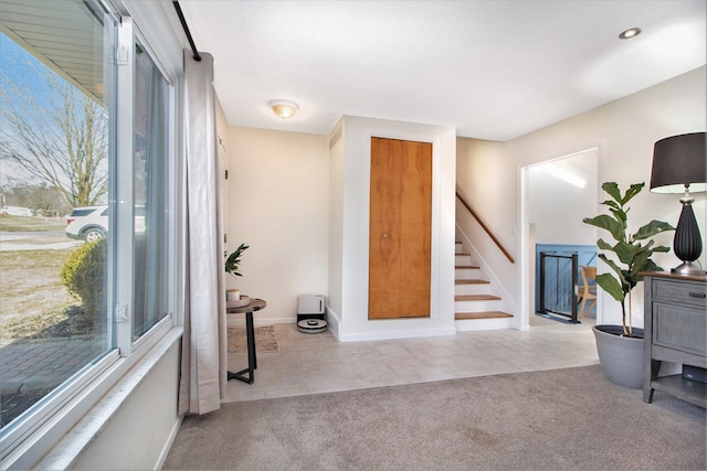 tiled foyer featuring stairway, baseboards, and carpet