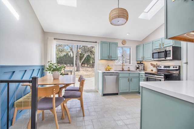 kitchen featuring light countertops, lofted ceiling with skylight, appliances with stainless steel finishes, and a sink