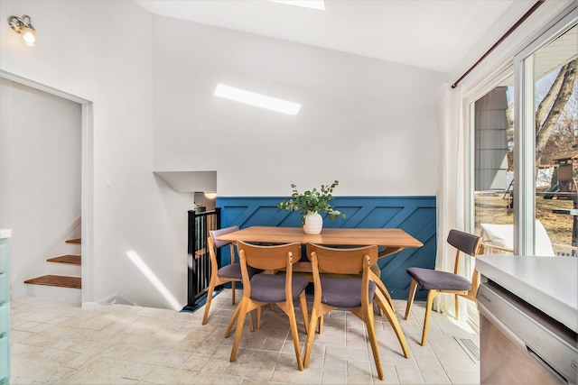 dining space with a wainscoted wall and stairway