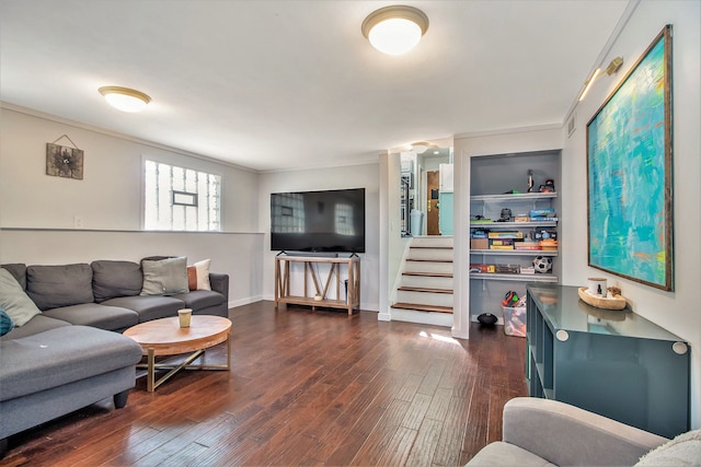 living area with crown molding, baseboards, dark wood finished floors, built in features, and stairs