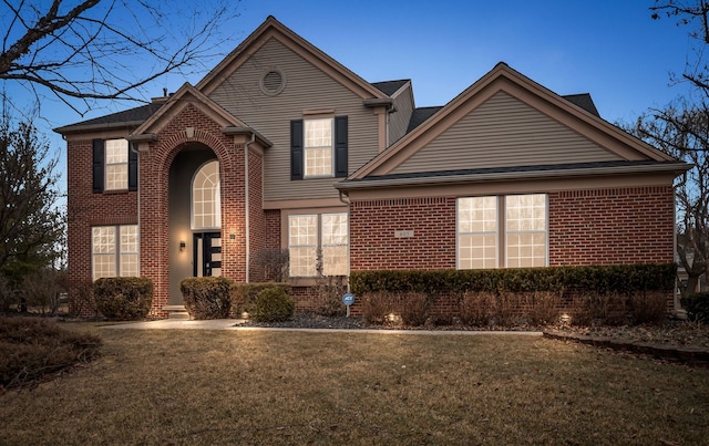 traditional-style home with a front yard and brick siding