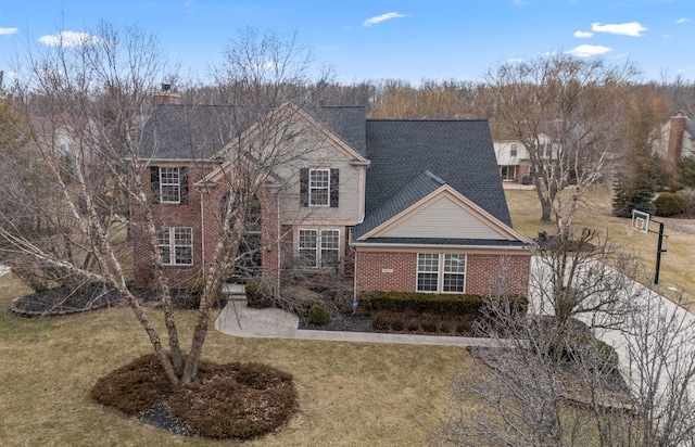 traditional home with brick siding, a chimney, and a front lawn