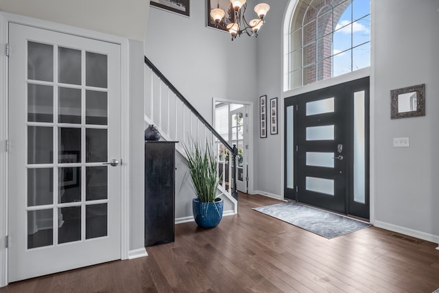 entryway with stairway, wood finished floors, baseboards, a high ceiling, and a chandelier