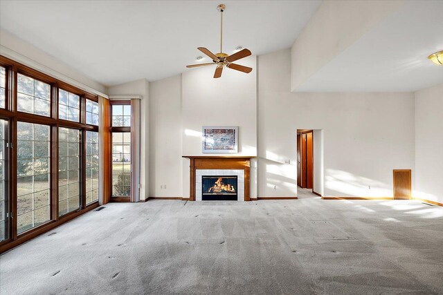 unfurnished living room with ceiling fan, baseboards, carpet floors, a tile fireplace, and high vaulted ceiling