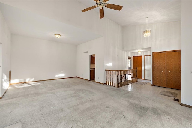 interior space featuring carpet flooring, ceiling fan with notable chandelier, baseboards, and a towering ceiling