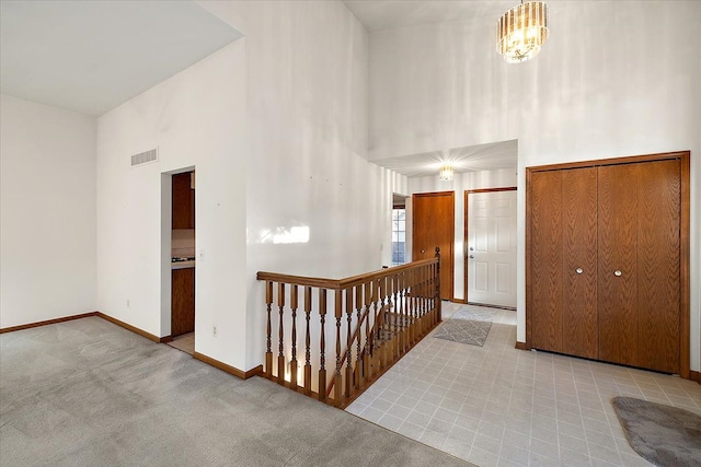 carpeted foyer with visible vents, baseboards, and a towering ceiling