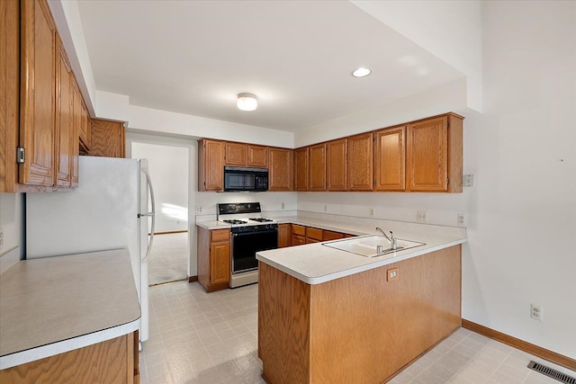 kitchen featuring visible vents, a sink, gas stove, a peninsula, and black microwave