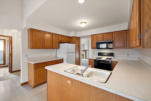 kitchen with freestanding refrigerator, a sink, black microwave, range with gas cooktop, and brown cabinets