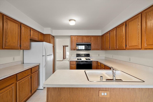 kitchen featuring range with gas cooktop, black microwave, light countertops, freestanding refrigerator, and a sink