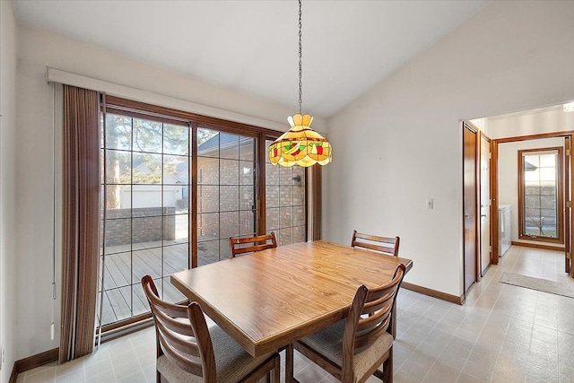 dining space featuring a wealth of natural light, baseboards, lofted ceiling, and light floors