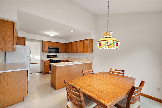 kitchen featuring range with gas stovetop, light floors, brown cabinets, and black microwave