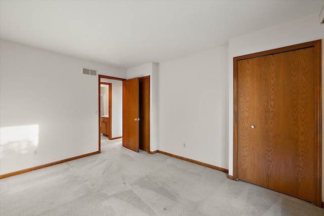 unfurnished bedroom with visible vents, light carpet, and baseboards