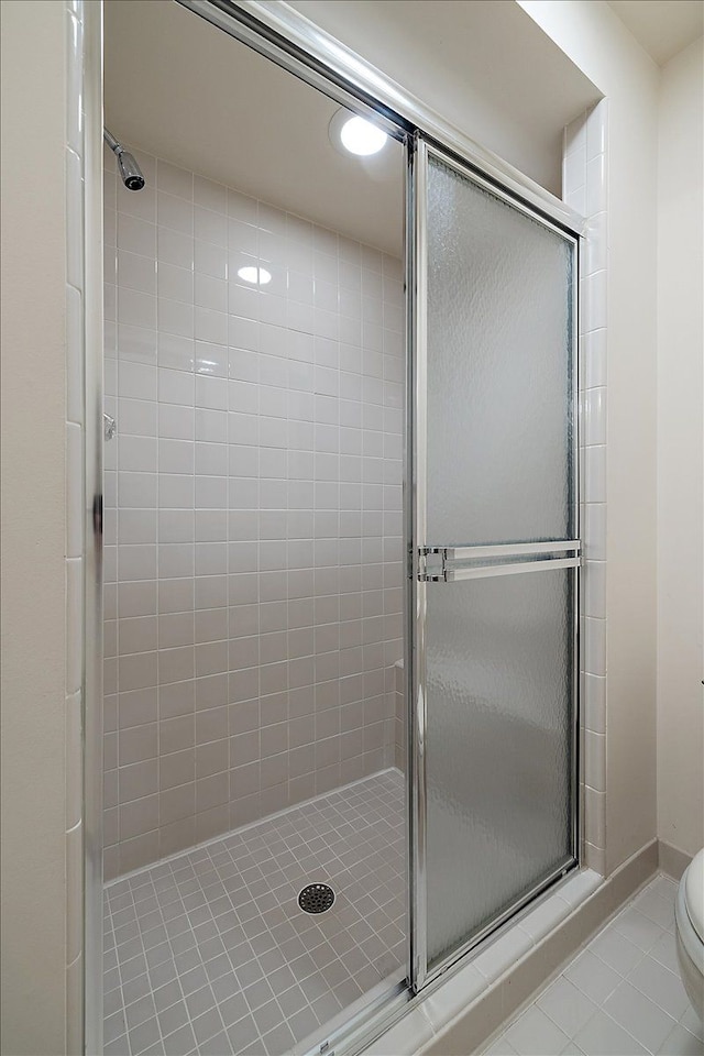 full bathroom featuring tile patterned floors, a shower stall, and toilet