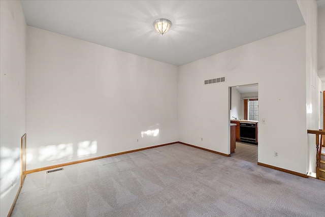 unfurnished room featuring visible vents, light colored carpet, and baseboards