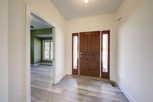 foyer with visible vents, wood finished floors, and baseboards