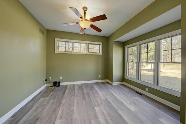 empty room featuring visible vents, baseboards, wood finished floors, and a ceiling fan