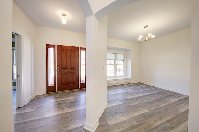 foyer entrance with an inviting chandelier, baseboards, and wood finished floors