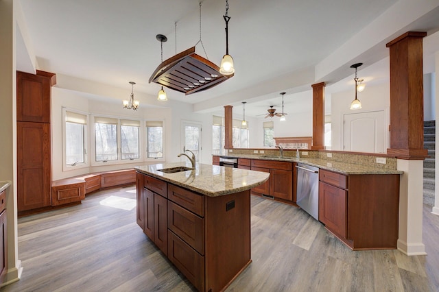 kitchen with a sink, light wood-style floors, stainless steel dishwasher, and a kitchen island with sink