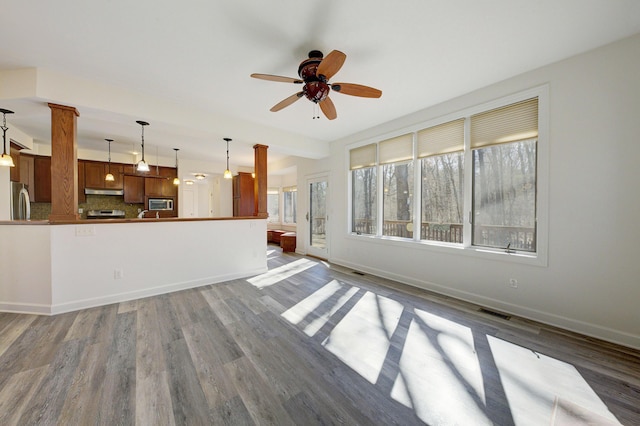 unfurnished living room with visible vents, baseboards, and wood finished floors