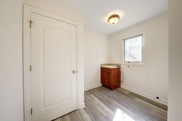 interior space with a sink, baseboards, and light wood finished floors