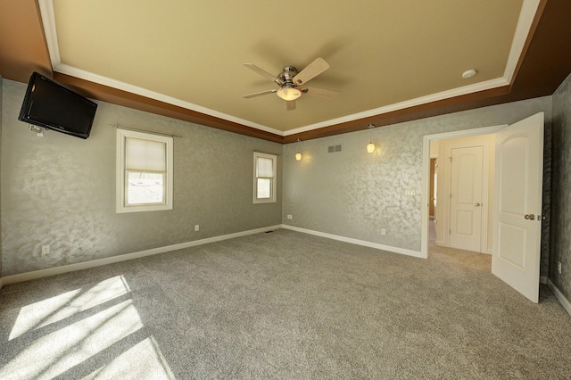 spare room featuring carpet, visible vents, ceiling fan, crown molding, and a raised ceiling