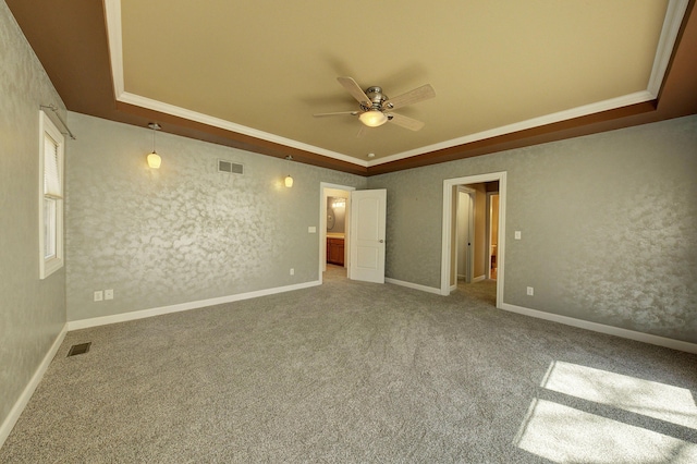 empty room with a tray ceiling, visible vents, carpet floors, and ceiling fan