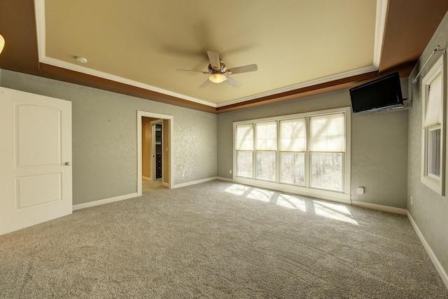 carpeted spare room featuring ceiling fan, baseboards, and a tray ceiling