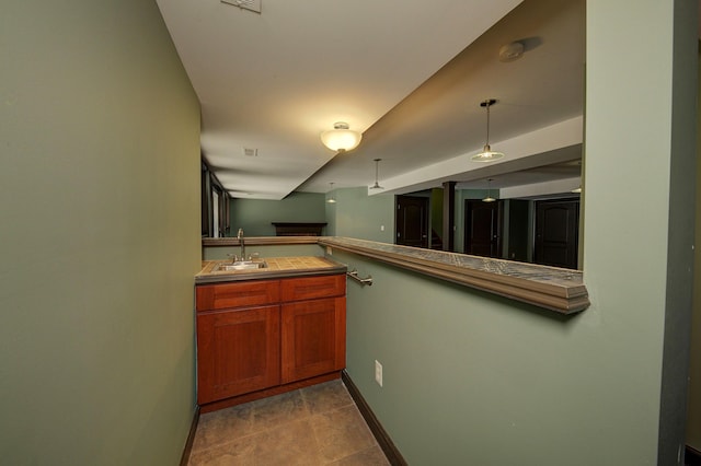 kitchen with brown cabinetry, decorative light fixtures, baseboards, and a sink