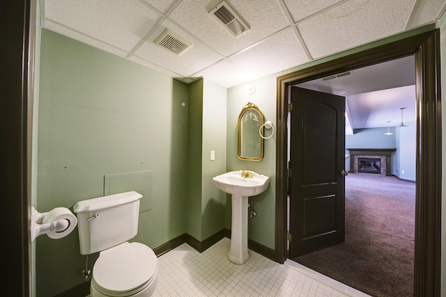 bathroom with a drop ceiling, visible vents, baseboards, and toilet