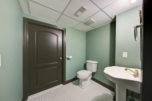 half bath with tile patterned flooring, visible vents, toilet, and a paneled ceiling