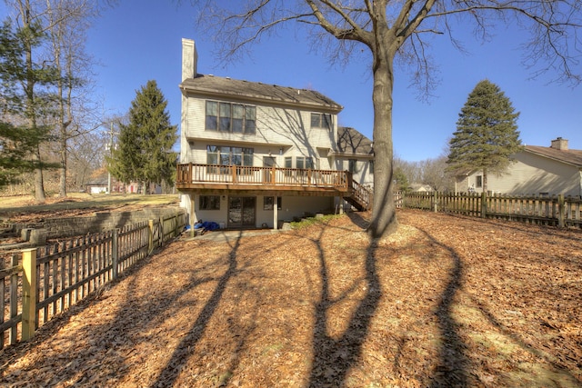 rear view of property with a wooden deck, a fenced backyard, and a chimney