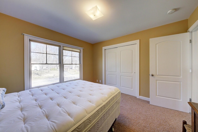 bedroom with a closet, light colored carpet, and baseboards