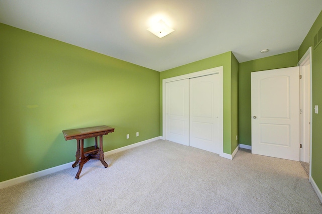 unfurnished bedroom featuring a closet, light colored carpet, and baseboards