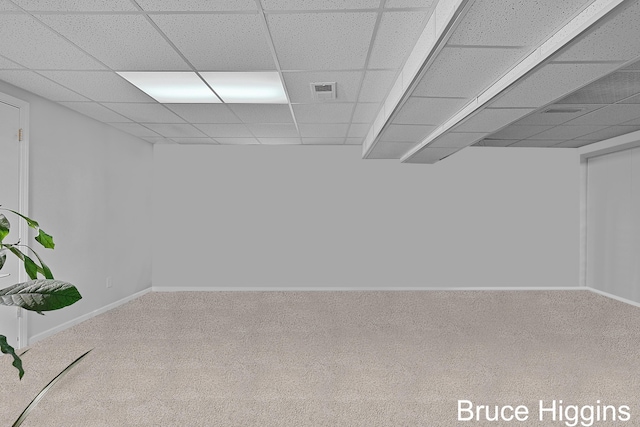 below grade area featuring a drop ceiling, visible vents, baseboards, and carpet flooring