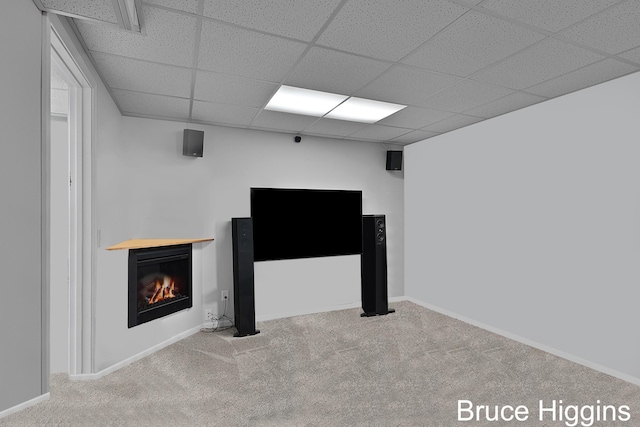 finished basement featuring a glass covered fireplace, carpet flooring, a paneled ceiling, and baseboards