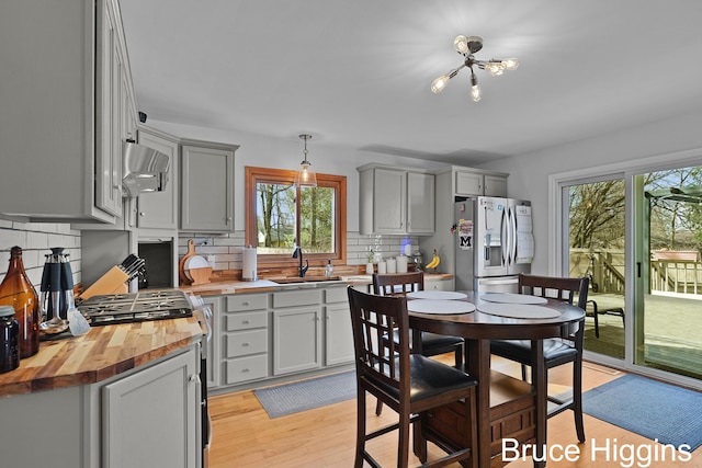 kitchen with a sink, stainless steel appliances, wooden counters, and gray cabinets