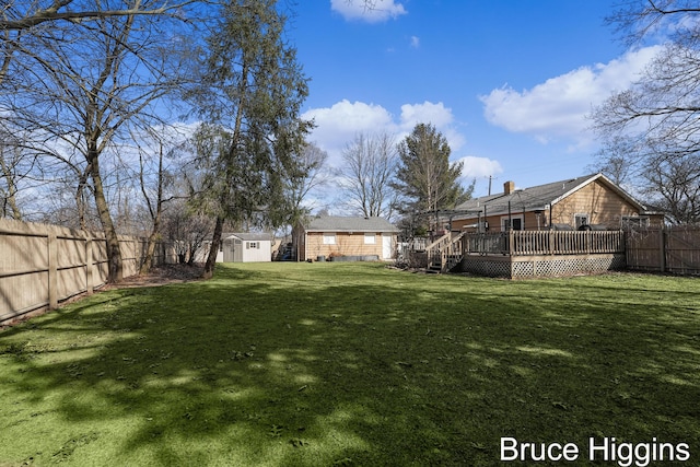 view of yard with a storage shed, an outbuilding, a fenced backyard, and a wooden deck