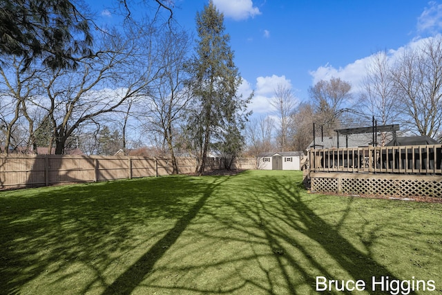 view of yard with a fenced backyard, an outdoor structure, a storage shed, and a deck