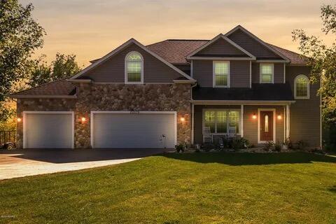 view of front of property with a front yard, stone siding, and driveway